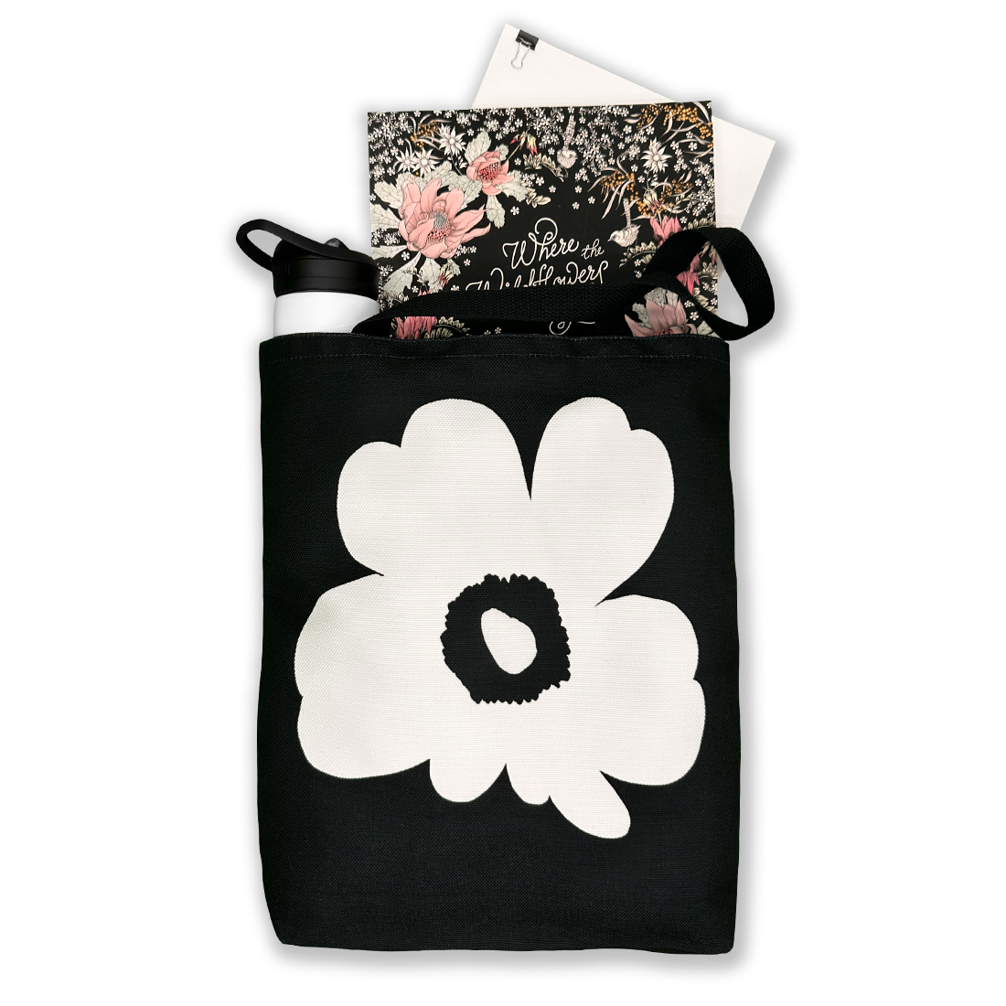 Black tote bag with white flower design, carrying books and a water bottle, ideal for school, work, or daily errands.