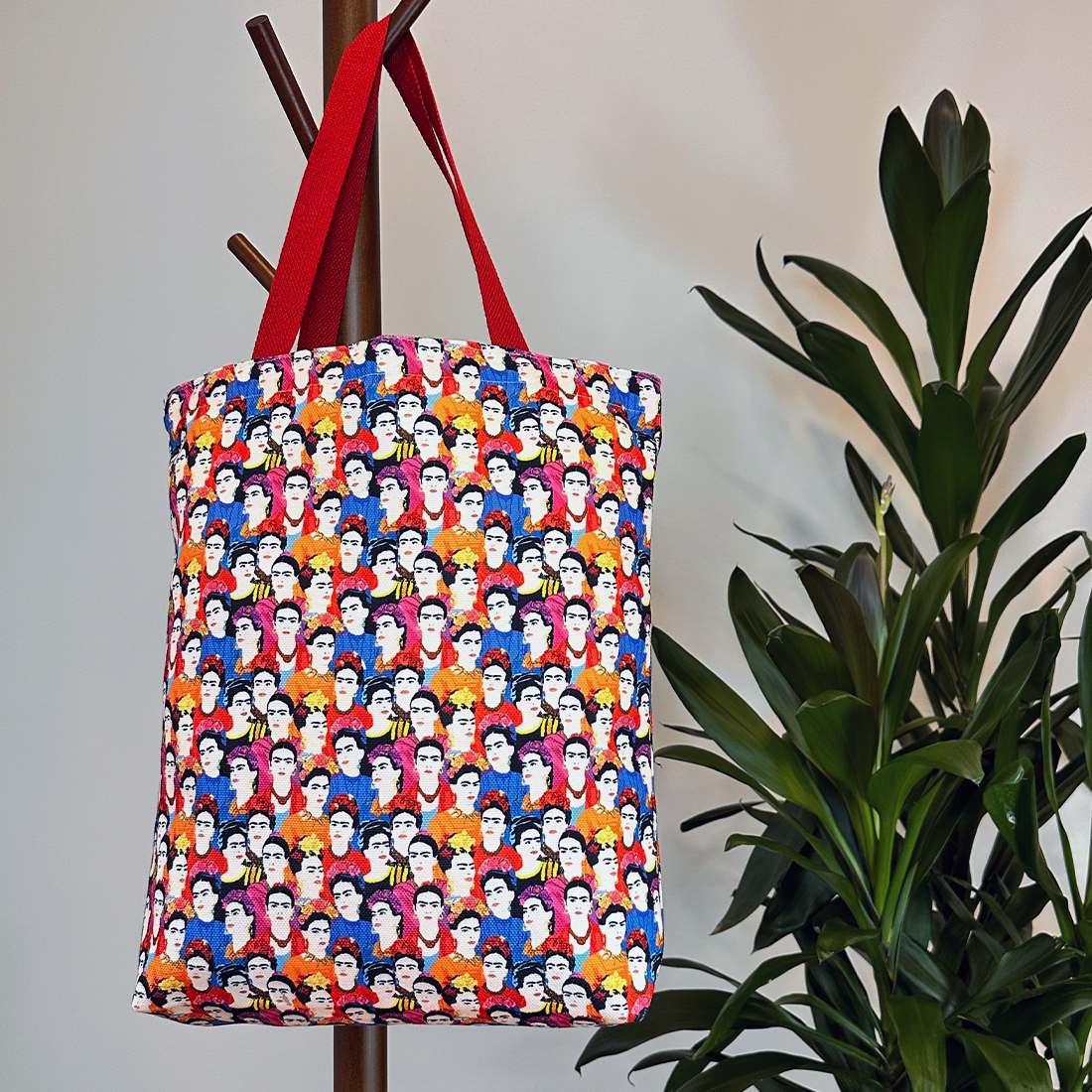 Lifestyle image of tote bag on a coat rack with a bright pop-art pattern and red strap, adding a colorful touch to the decor.